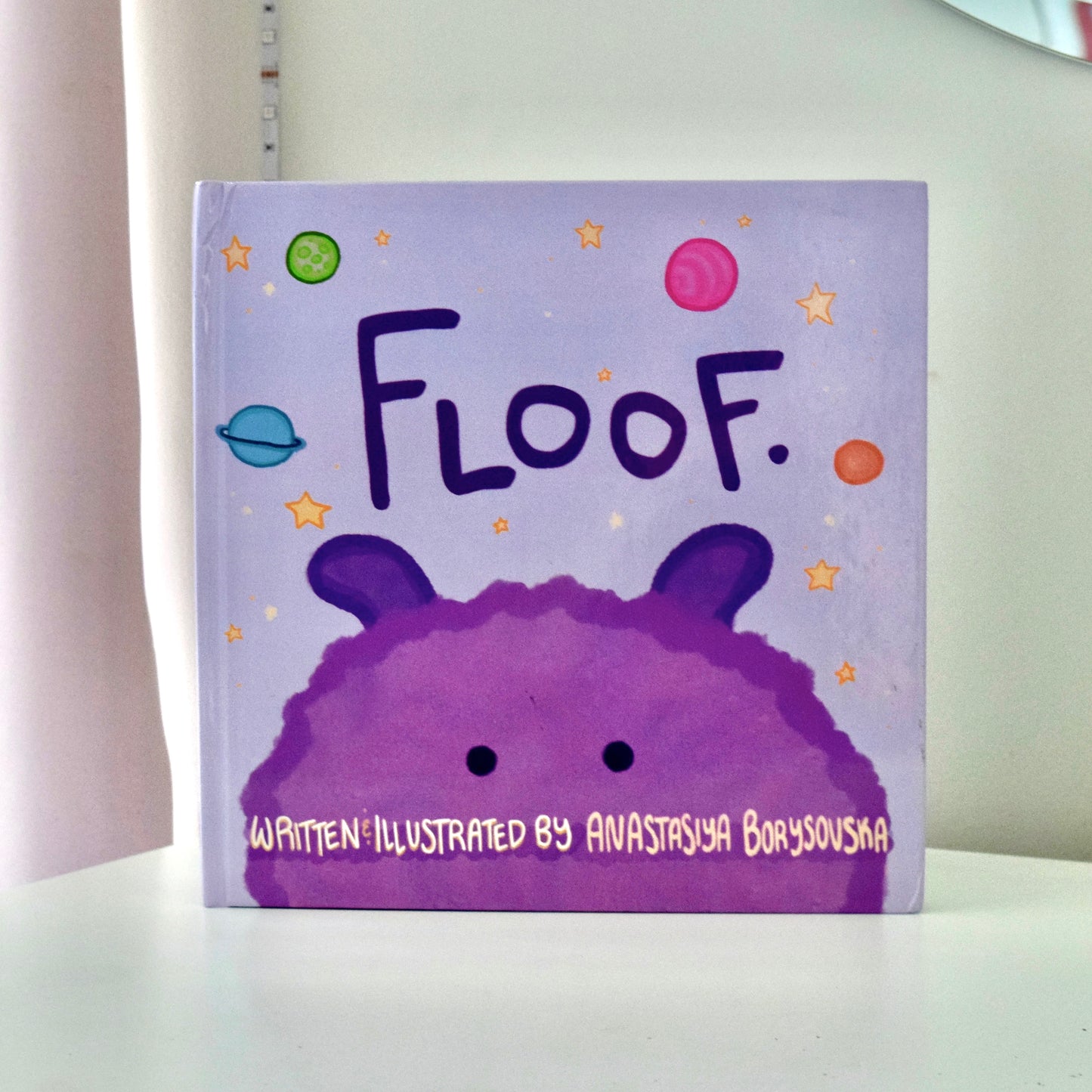 Story book with a furry purple Floof. Pictured in space.